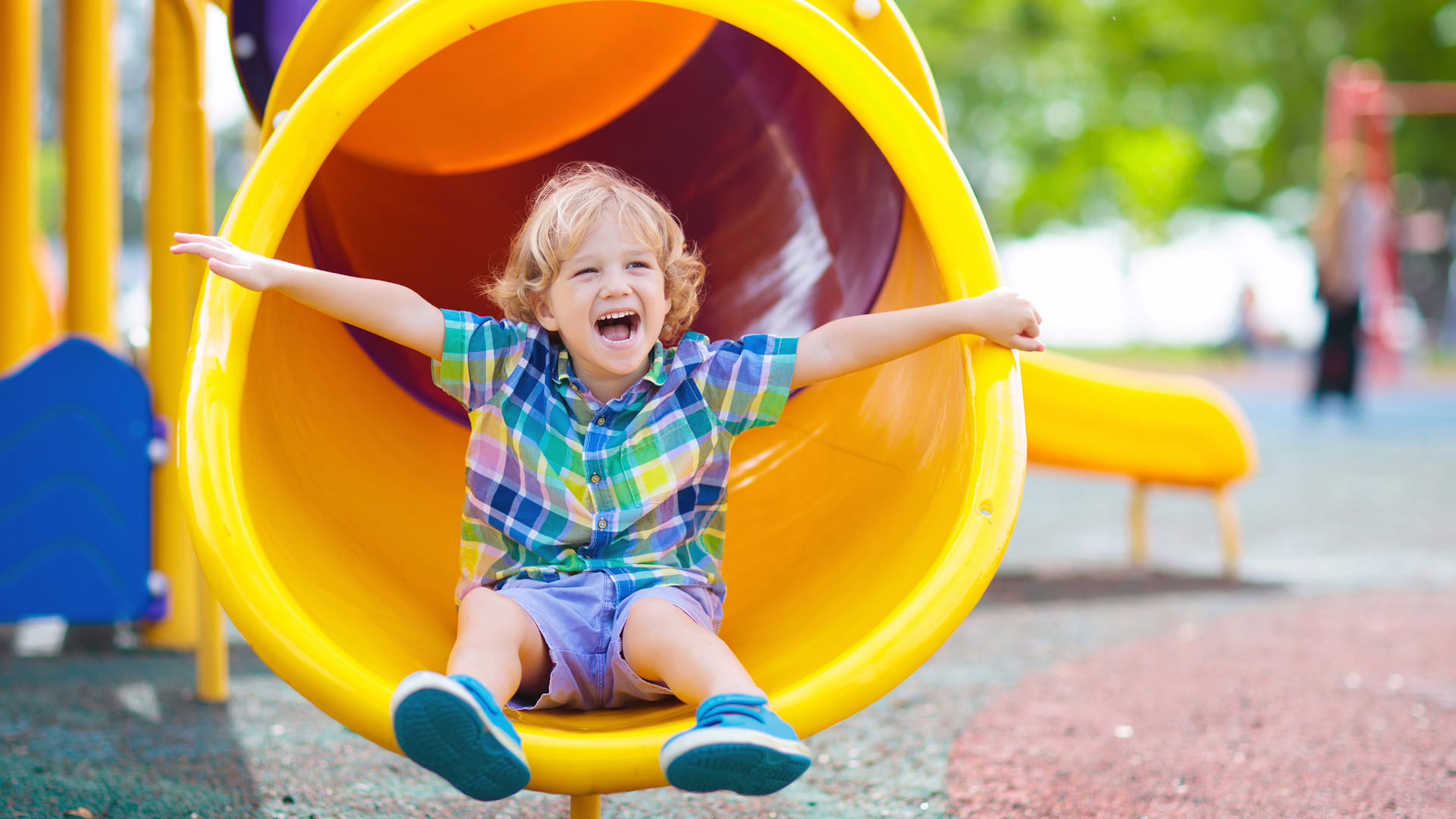 Ein Kind ist auf einem Spielplatz und ist am Ende der Rutsche angekommen.