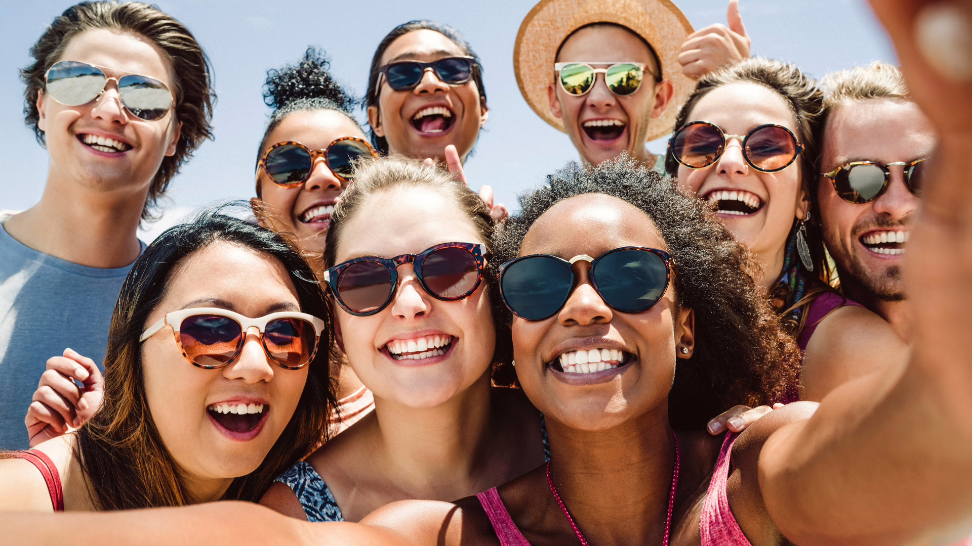 Eine junge Freundesgruppe mit Sonnenbrillen nehmen ein Selfie in der Sonne auf.