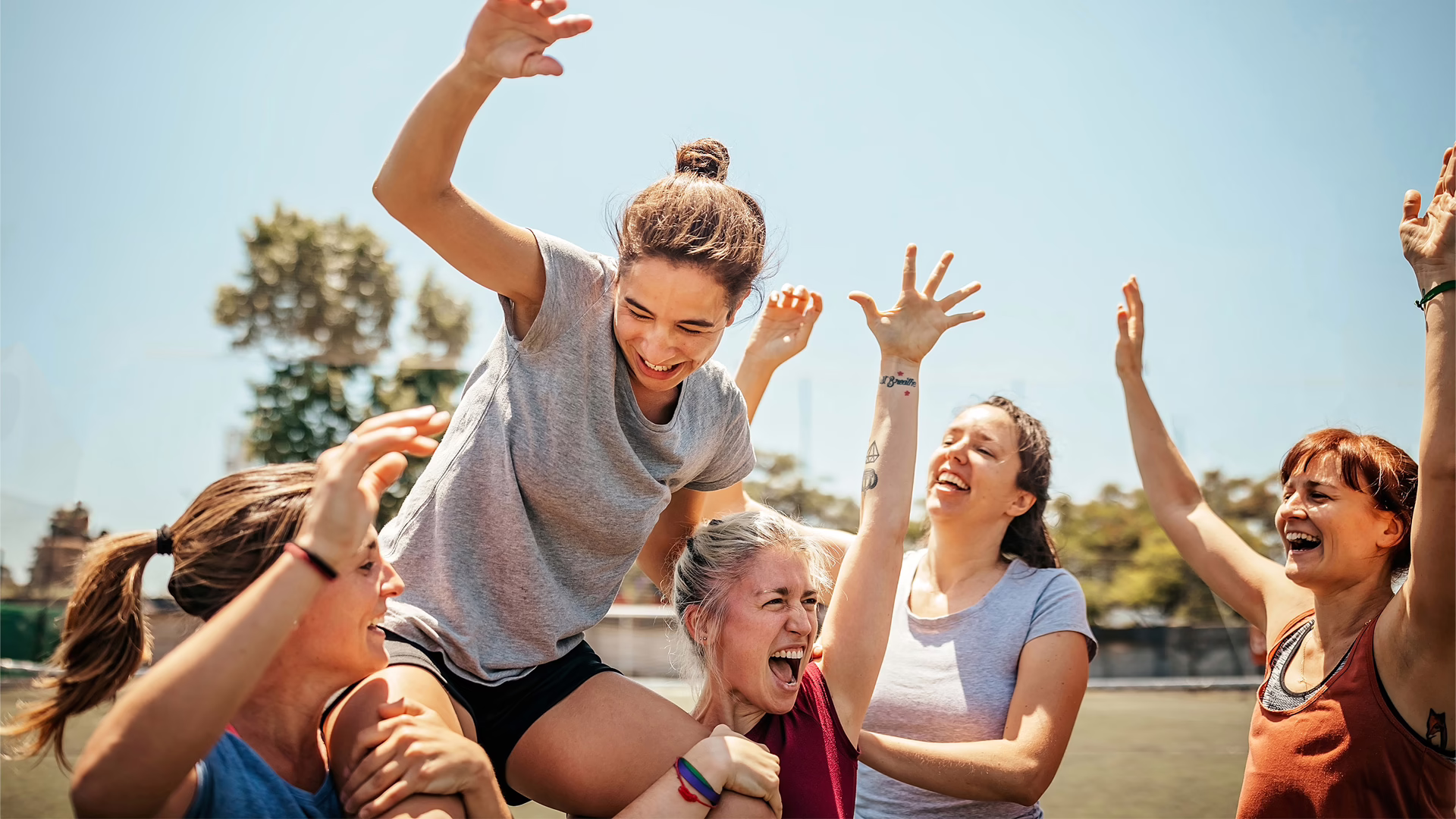 Frauen-Fußballmannschaft jubelt gemeinsam, während eine Spielerin getragen wird.