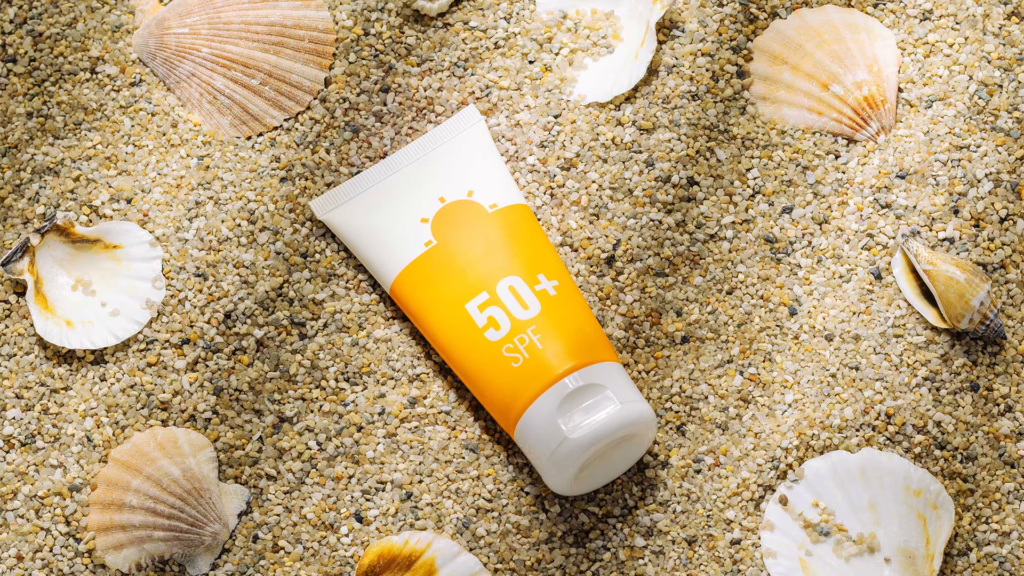 Eine Sonnencreme liegt auf einem Sandstrand. Sie ist mit einem Lichtschutzfaktor gekennzeichnet.