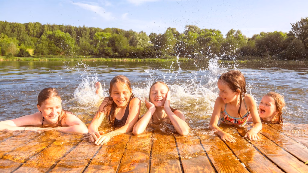 Glückliche Gruppe von Mädchen, die Spaß daran haben, in einem See zu spielen und zu planschen.